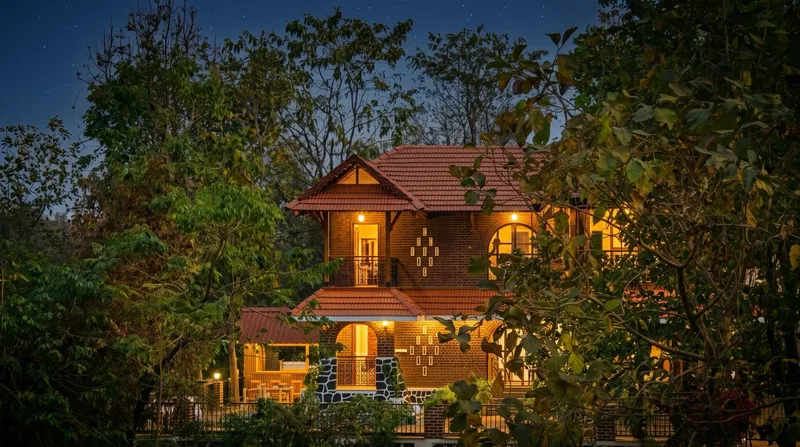 Brick and timber villa with a tiled roof at dusk, with bougainvillea beside the entrance steps